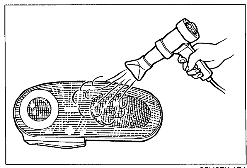 Hand using a hot air blower (heat gun) directed at the perimeter of the rear combination light lens to soften the 'hot melt' bonding agent (Step 1).