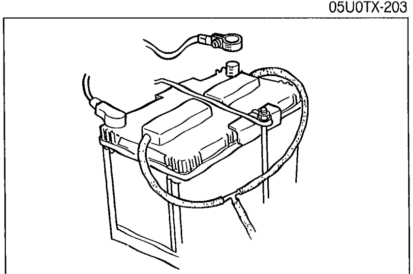 Photo of the battery in the engine bay with the negative cable being disconnected.