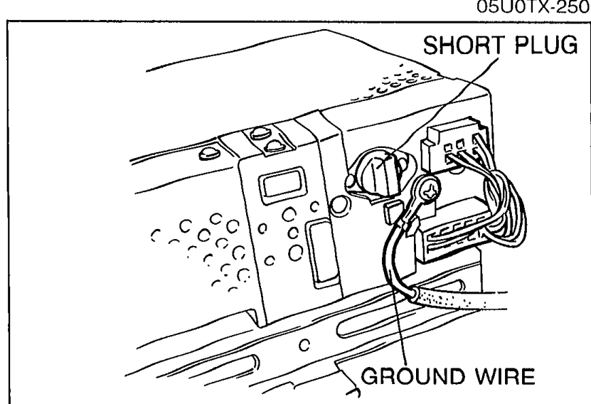 Rear view of removed audio unit showing wiring harness with labeled SHORT PLUG and GROUND WIRE connections. Reference for Step 2 connection inspection.