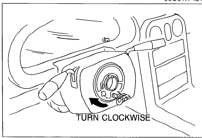 Close-up of the clock spring connector with a rotational arrow and the label 'TURN CLOCKWISE'. Shows turning the clock spring connector clockwise until it stops.