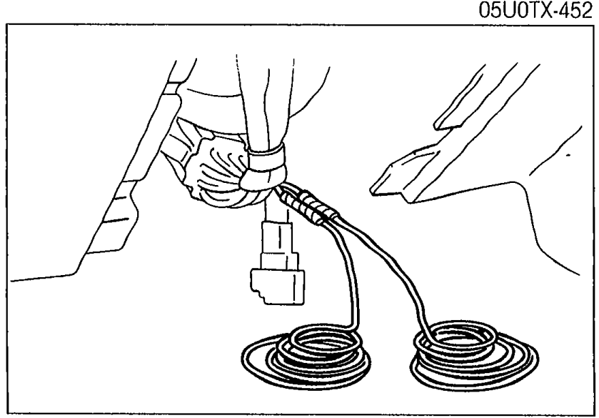Hands connecting two long jumper wires (coiled cables) to the clock spring cut wires for remote deployment.