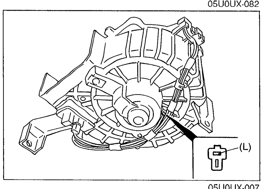 Illustration of the blower motor mounted under the dash with the connector pulled out and terminal (L) — Blue wire — highlighted on the connector for voltage measurement.